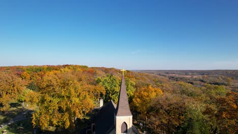 small country catholic church and old cemetry in colorful rural autumn forest drone