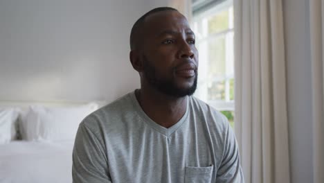 Thoughtful-african-american-man-sitting-on-the-bed-at-home