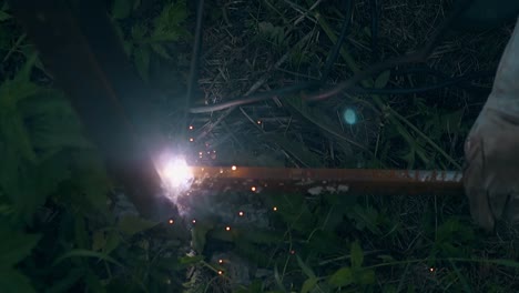 slow motion builder welds foundation of fence in darkness