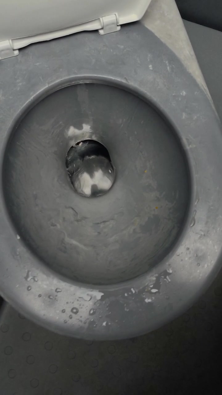 Close-up view of water moving inside a grey plastic portable restroom seat during transport.