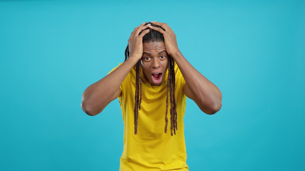 Shocked man with dreadlocks in a yellow shirt
