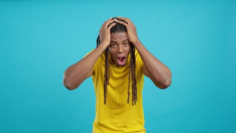 Shocked man with dreadlocks in a yellow shirt