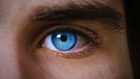 a slow motion close up shot of an artificial looking blue eye reacting to light changes