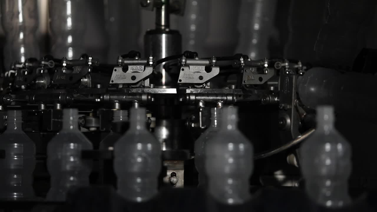 Close Up Shot of Plastic Bottles on a Rotating Machine at a Factory Being Prepared to be Filled with Fresh Vinegar