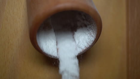 rice flour puring out of the milling machine and falling into a bowl - slow motion close up