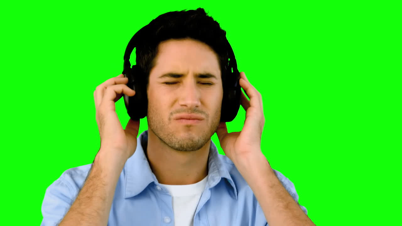 hombre escuchando música con auriculares en la pantalla verde