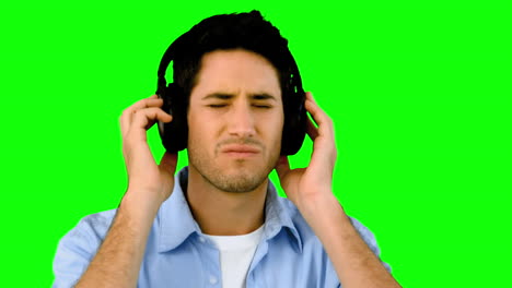 hombre escuchando música con auriculares en la pantalla verde