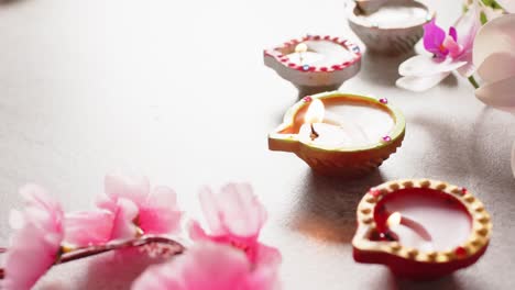 Burning-colourful-candles-celebrating-diwali-with-copy-space-and-flowers-on-white-background