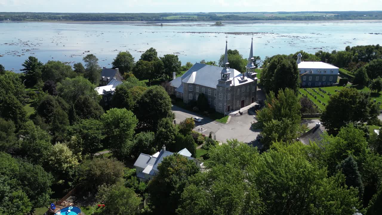 Etableringsbild i luften av kyrkogård omgiven av skog och vatten i Quebec, Kanada