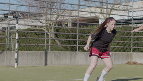 sporty teenaged girls playing soccer at open air pitch