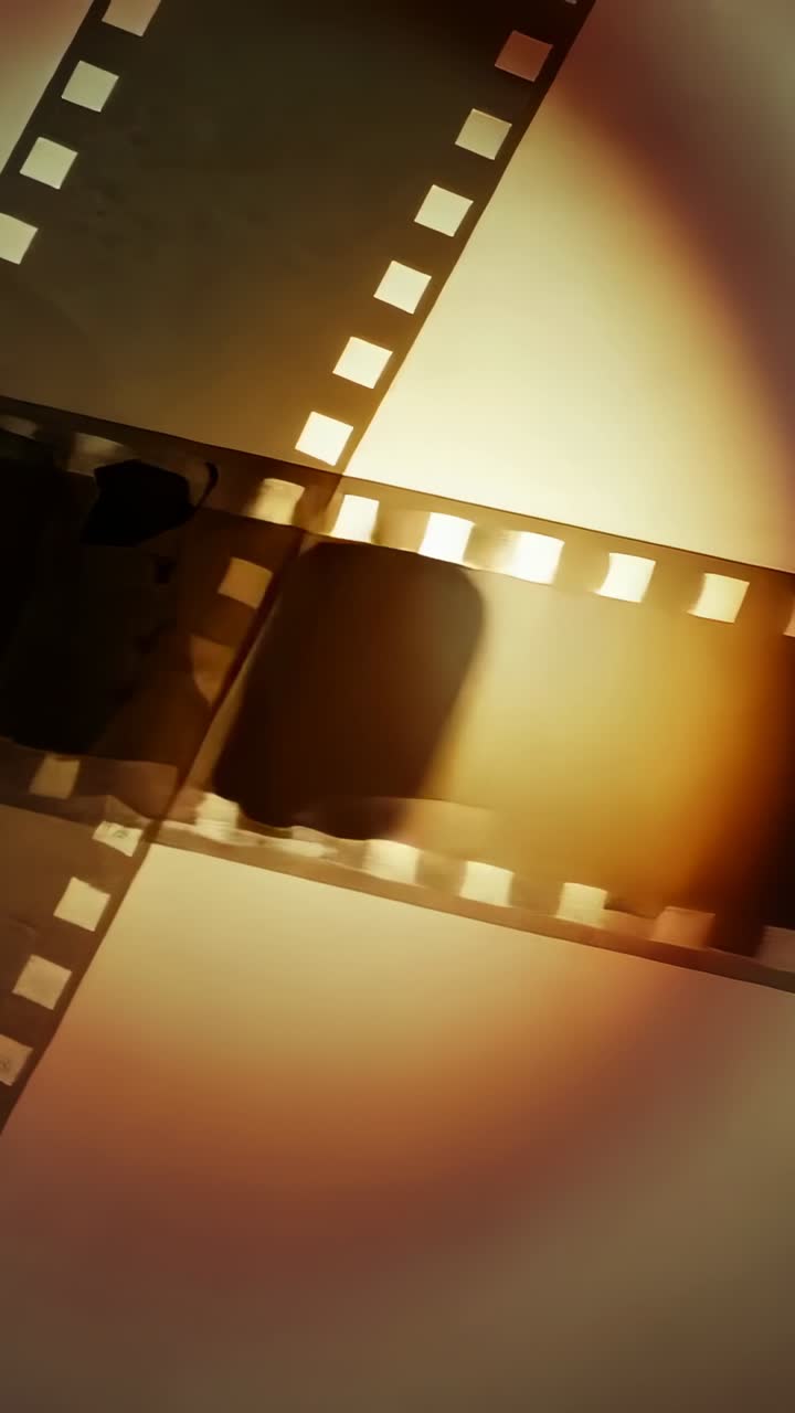 Vertical video: Shifting filmstrip overlay with sprockets gliding on paper as warm light rising