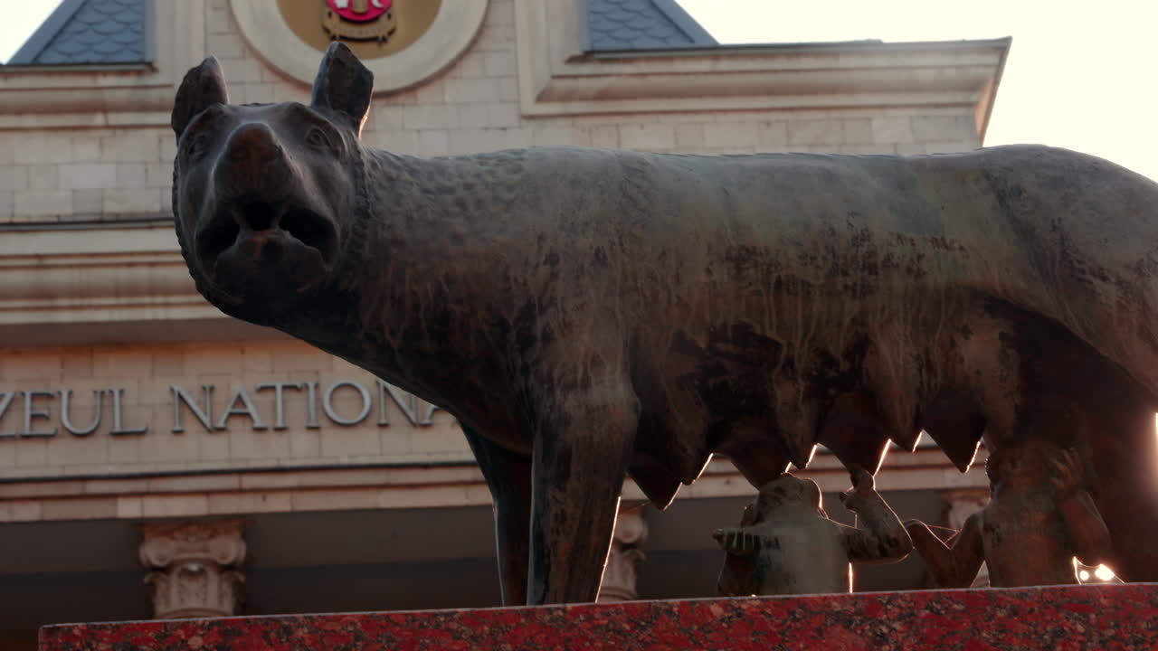 Chisinau, Moldova - September 25, 2025: Historic bronze statue of the Capitoline Wolf with Romulus and Remus on a red marble pedestal in front of the National History Museum of Moldova