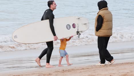 father and son walking with surfboard on beach