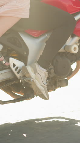 vista en primer plano de dos mujeres montando una bicicleta eléctrica en movimiento, las piernas del ciclista están vestidas con zapatillas de deporte, mientras que el pasajero lleva sandalias, con el vestido revoloteando en el viento a medida que la bicicleta se mueve