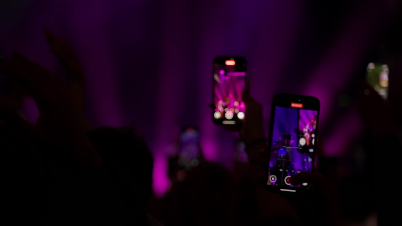 Koncertgæster filmer liveoptræden med smartphones og scenelys