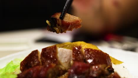 palillos para comer levantando una pieza de pato asado del plato