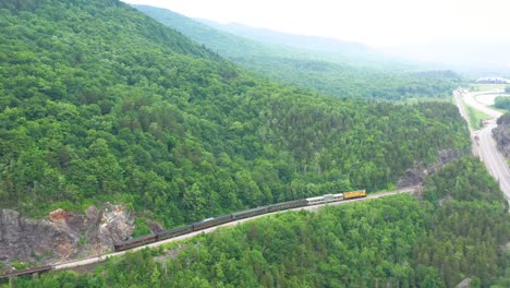 drone flying backwards over train passing in mountain of new hampshire landscape