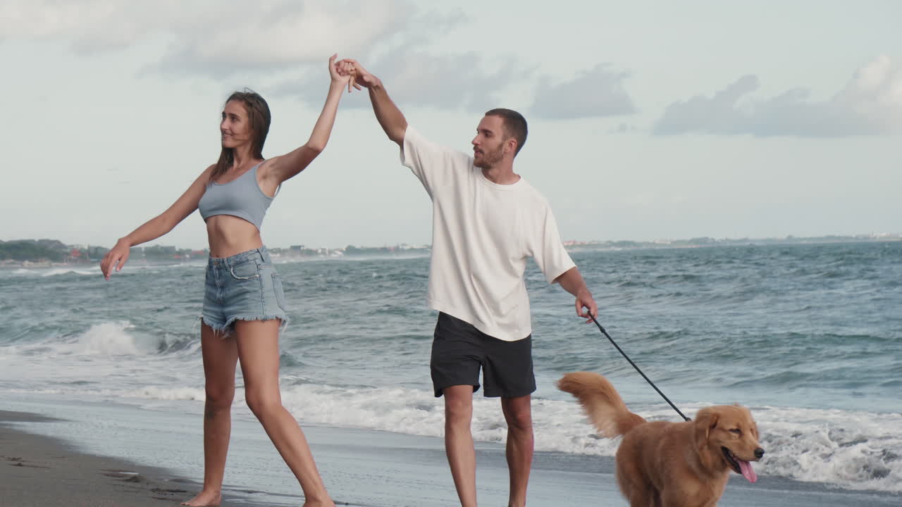 una pareja amorosa paseando con un perro a lo largo del océano.