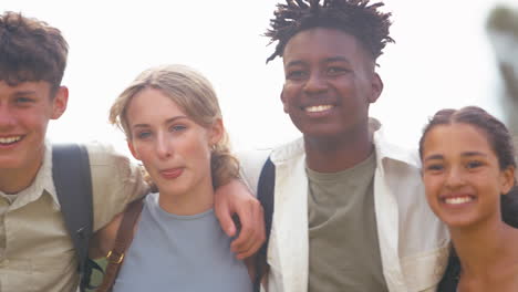 close-up portret van glimlachende multiculturele middelbare school of middelbare scholieren die buiten op de muur zitten