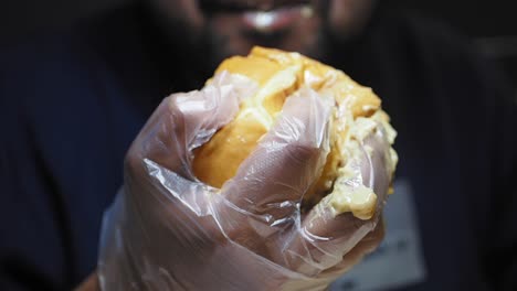 person eating a burger with gloves