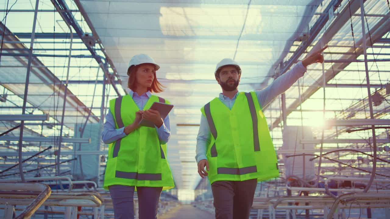 Two warehouse workers inspecting production preparations in greenhouse talking