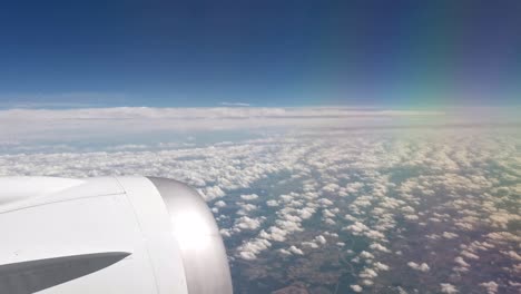 el motor de un avión grande frente a un horizonte azul y la tierra debajo