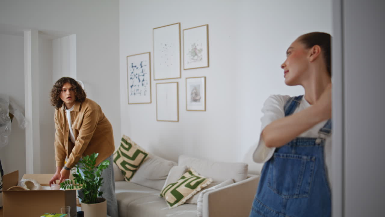 Young woman decorating wall by hanging artwork closeup. Happy wife asking man