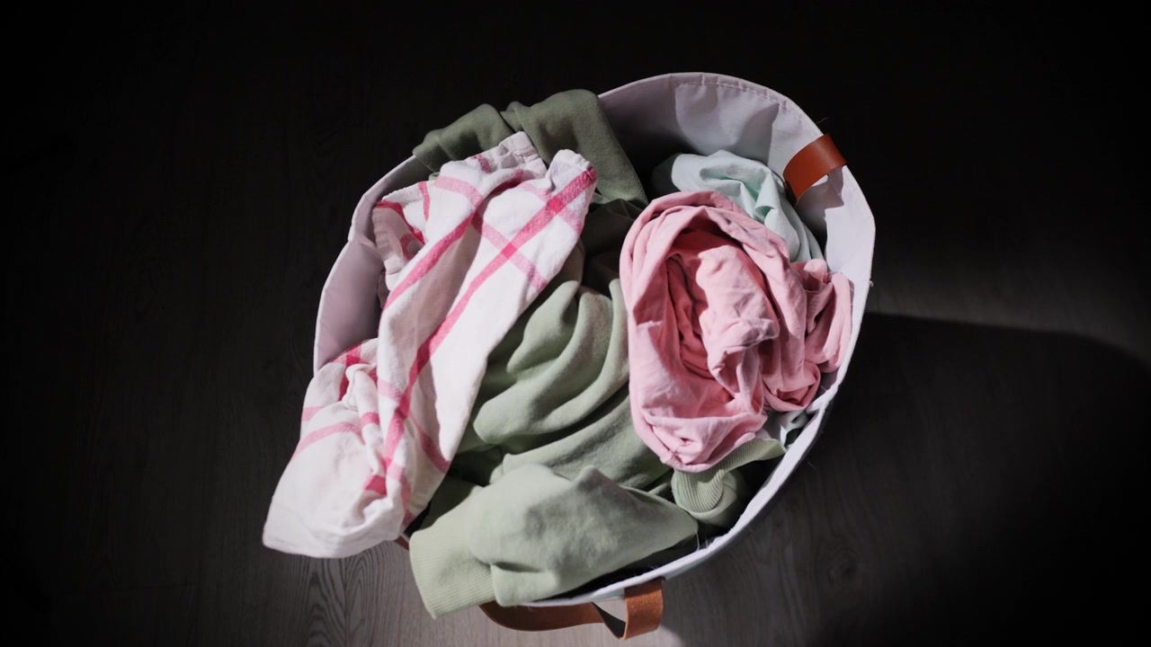 Topdown view of laundry basket being filled with dirty clothes