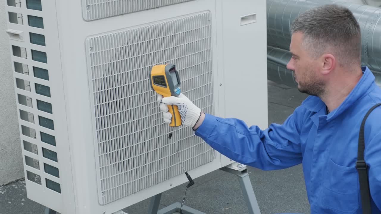 Technician uses a thermal imaging infrared thermometer to check the condensing unit heat exchanger