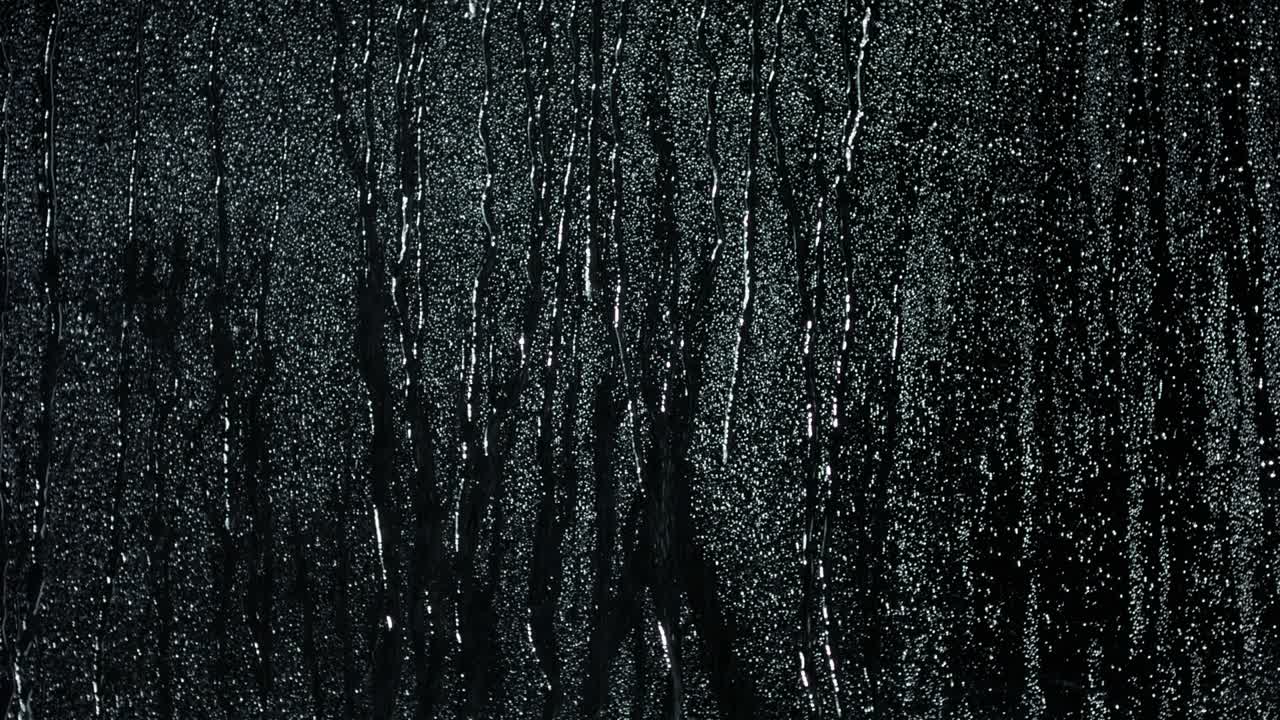 gotas de agua en el vidrio negro corriendo hacia abajo