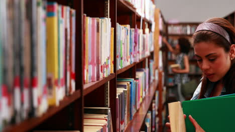 Estudiante-Sonriente-Escogiendo-Un-Libro-De-Texto-En-La-Biblioteca