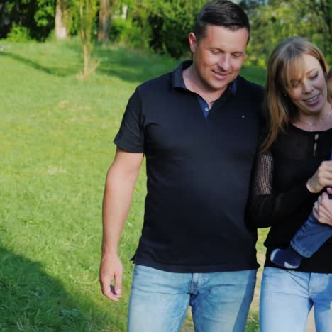 Una-Joven-Familia-Caucásica-Está-Caminando-Con-Un-Hijo-En-El-Parque-1