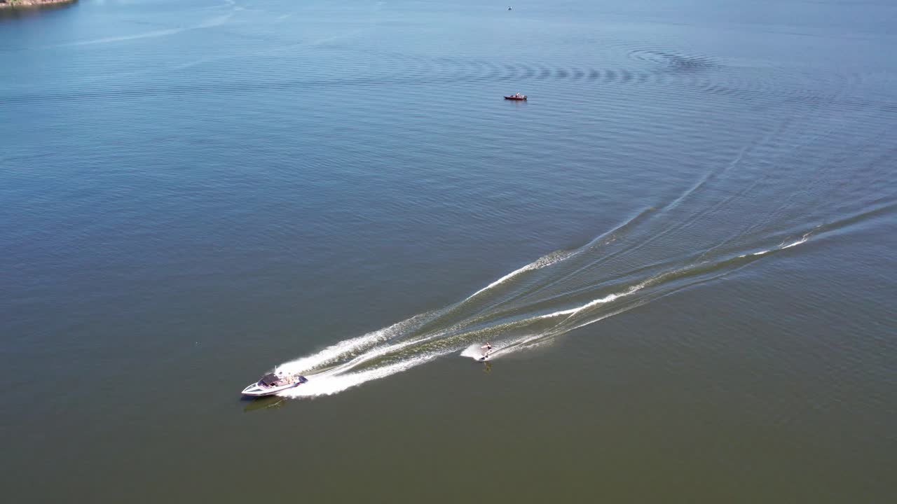 Panning aerial footage of a speed boat pulling a wakeboarder on lake Eildon, near Mansfield in central Victoria, Australia.