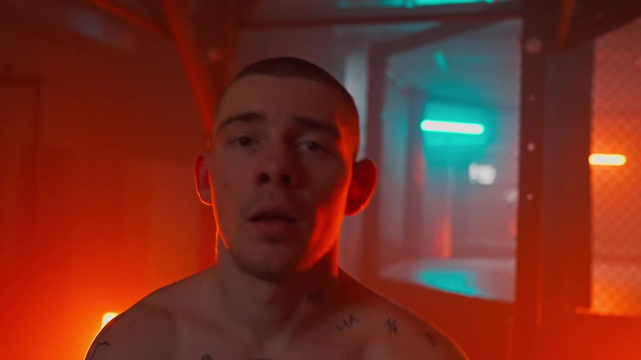 Ritratto intenso di un uomo tatuato sotto una luce al neon rossa e blu