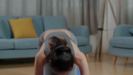joven entrenadora asiática mujer en ropa deportiva hablando y haciendo yoga en la postura de tabla del antebrazo mientras enseña ejercicios en casa