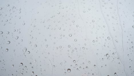 se ve a través de un vidrio de ventana una filmación cercana en cámara lenta de fuertes gotas de lluvia