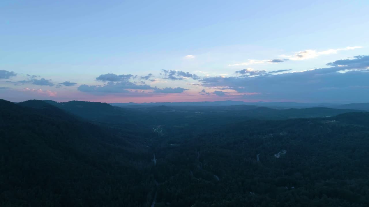 Drone flyver gennem en bjergkæde ved solnedgang.