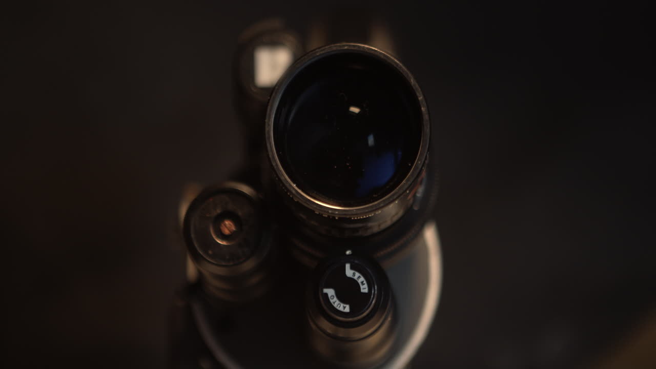 Macro con carrello laterale di un obiettivo vintage da 16mm per cineasta con ghiera di messa a fuoco testurizzata. Dettaglio di attrezzatura cinematografica analogica per uso di produzione e media