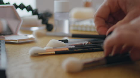 lady hands sorting makeup brushes at table close up. woman examining equipment