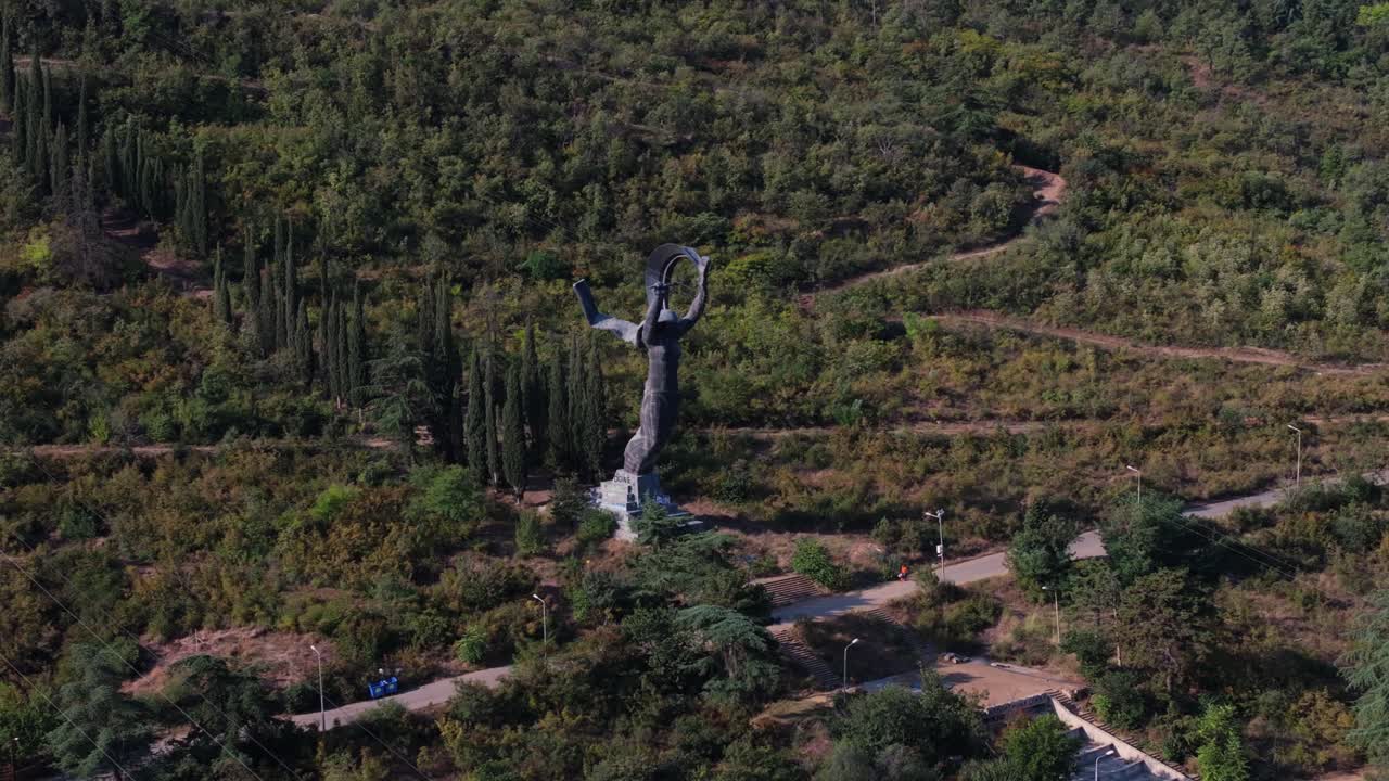Establishing Drone Shot Above Victory Statue in Vake Park, Tbilisi, Georgia, surrounded by greenery and road with car