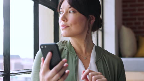 mujer, teléfono y visión por la ventana del apartamento