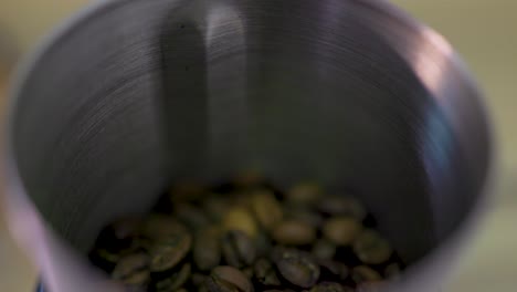 macro shot of coffee beans being poured into a coffee grinder to help make a delicious tasty beverage in the morning