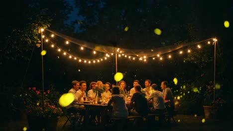 a magical night under string lights: friends gather for a memorable outdoor dinner surrounded by glowing fireflies in an enchanting garden setting