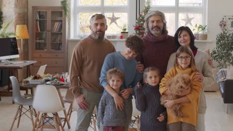 lächelnde familie, die kamera im wohnzimmer mit tisch- und weihnachtsdekorationen betrachtet