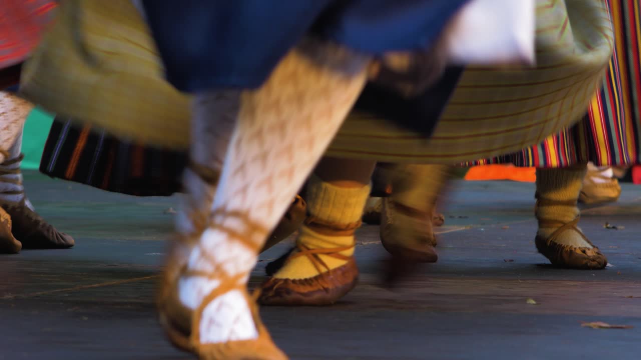 bailarinas adultas con trajes folclóricos tradicionales actúan en un espectáculo de danza al aire libre, feliz cultura nacional letona, primeros planos de pies con calzado simple hecho de una pieza de cuero