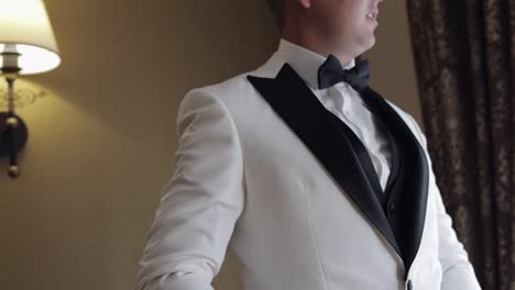 el novio se prepara en un tuxedo blanco para su día de bodas.