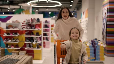 acción divertida de la madre y el hijo van al comercio moderno o centro comercial con carrito
