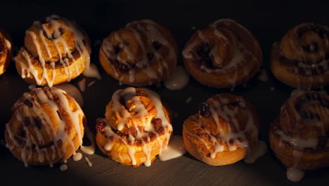 drizzling icing on top of freshly baked cinnamon rolls. overhead shot