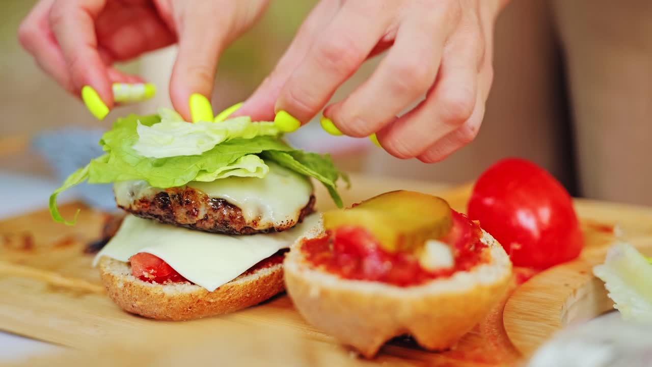 Slow motion closeup of fresh grilled burger pressed together during picnic prep