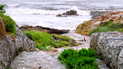 Vista-Con-Teleobjetivo-De-La-Escorrentía-De-Agua-De-Lluvia-Canalizada-Por-Muros-De-Gaviones-Hacia-El-Océano